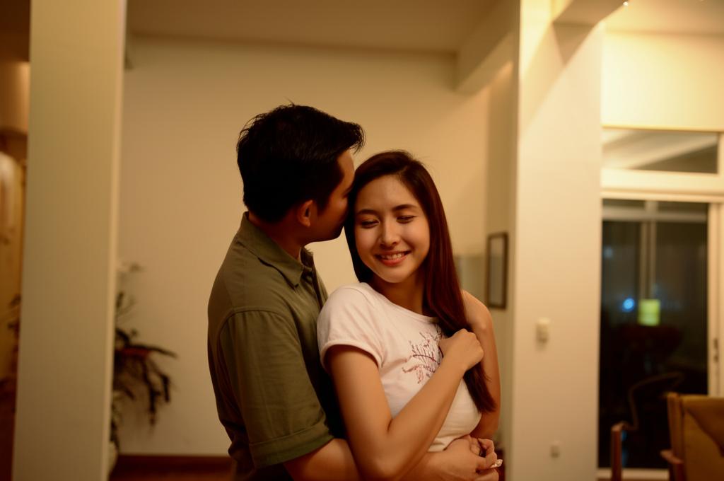 Happy couple embracing intimately, Singaporean apartment setting, warm lighting.