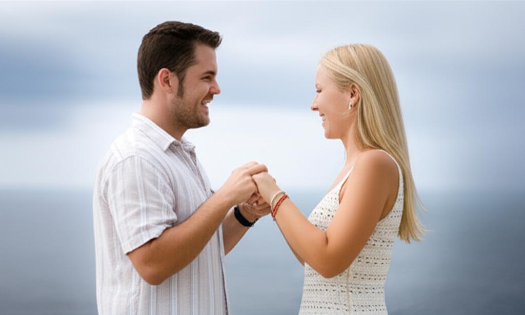 A couple holding hands and smiling, looking happier and more connected after overcoming challenges.